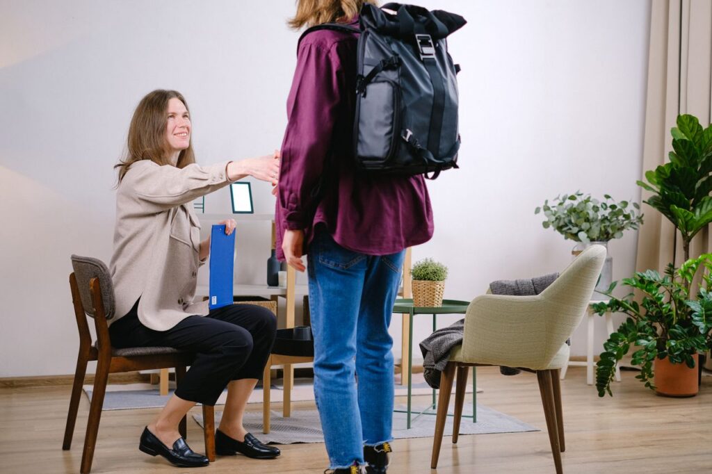 A therapist extends a handshake to welcome a new client in a cozy office setting.