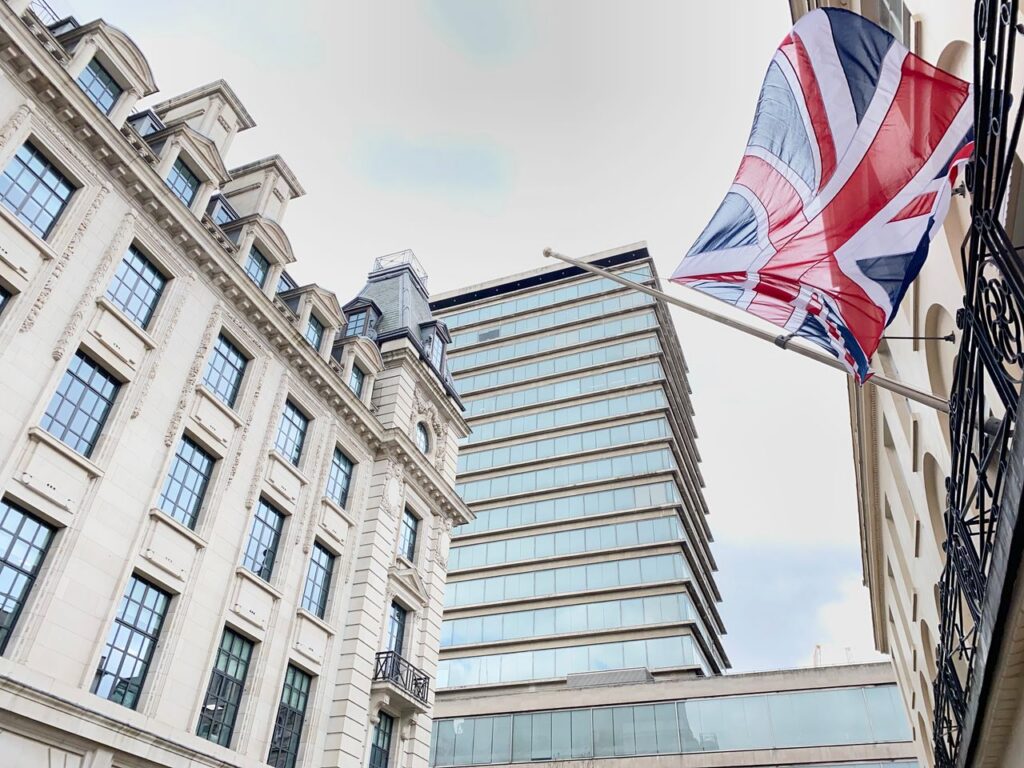 A striking view of London buildings adorned with a Union Jack flag fluttering in the wind.